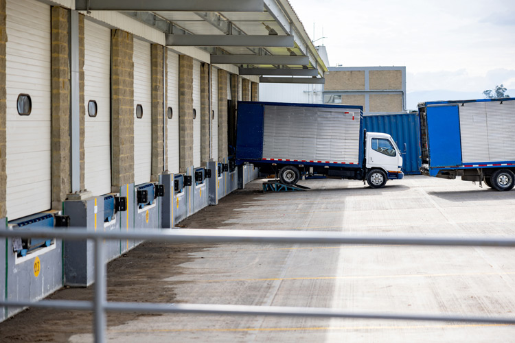 Lastbilar parkerade vid ett distributionslagers lastkaj under pågående lastning av gods, ett koncept för frakttransport och logistik.