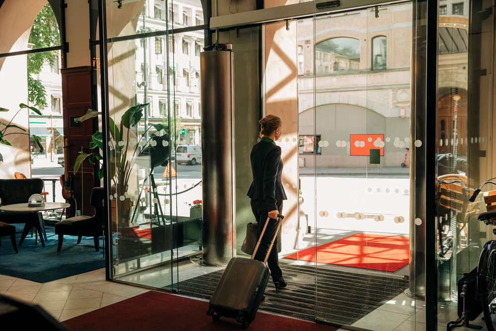 En medelålders affärskvinna i mörk kostym ses bakifrån när hon lämnar ett hotell i Stockholm